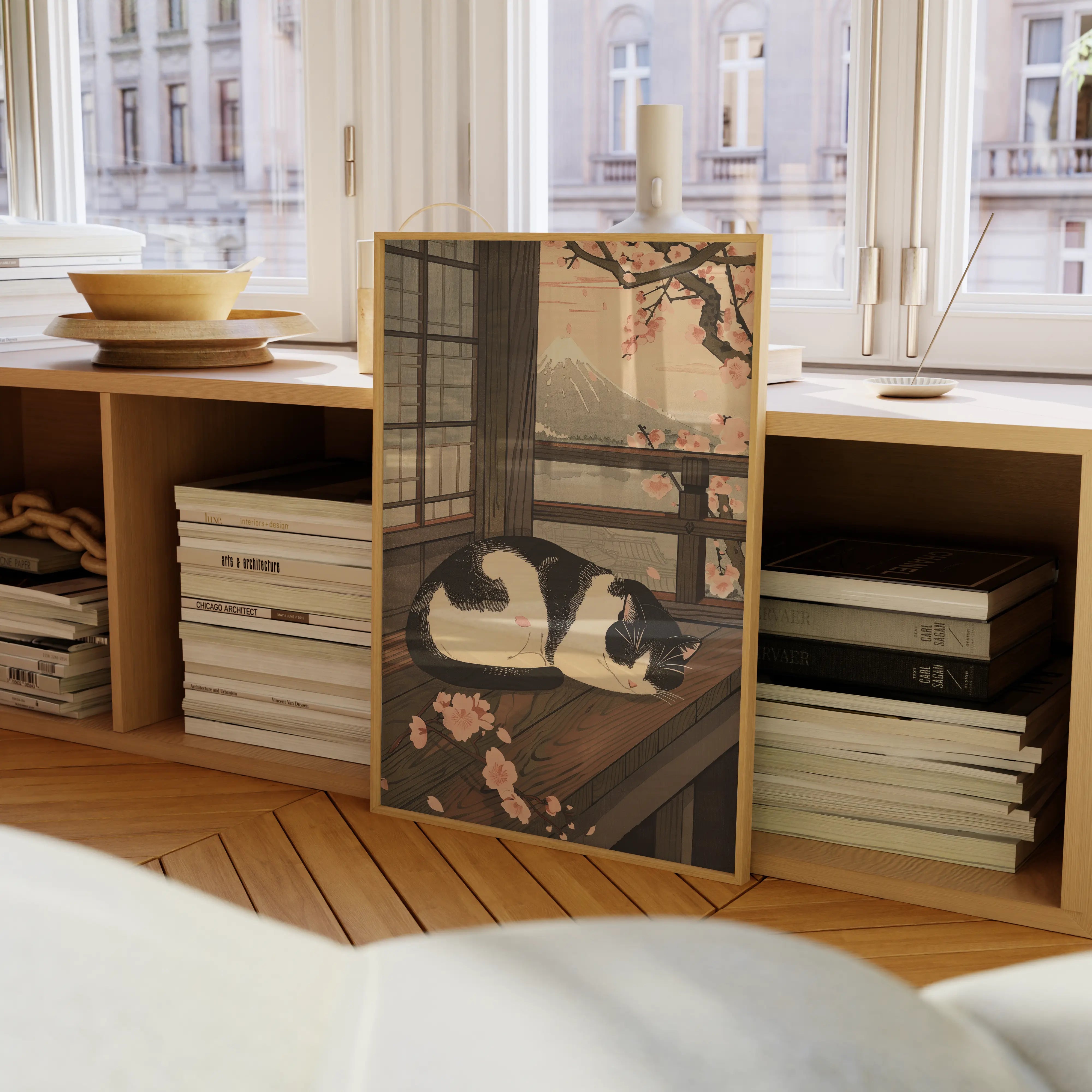 Sleeping Cat in Spring Japanese wall art print in a natural wood frame placed on the floor, leaning on a sideboard below a window