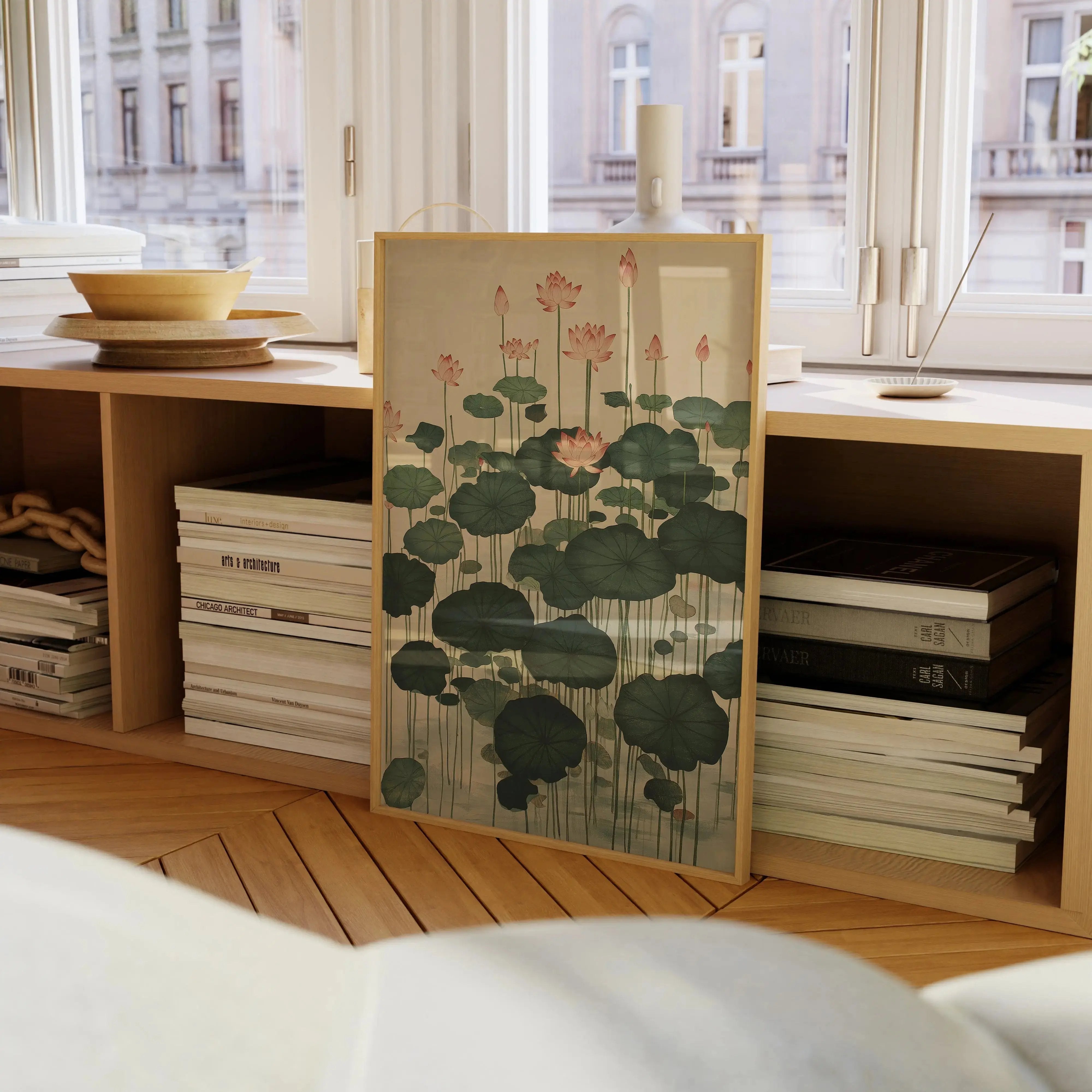 Japanese wall art print “Lotus Forest” featuring pink lotus blossoms and green lily pads leaning against a wooden shelf beneath a sunlit window